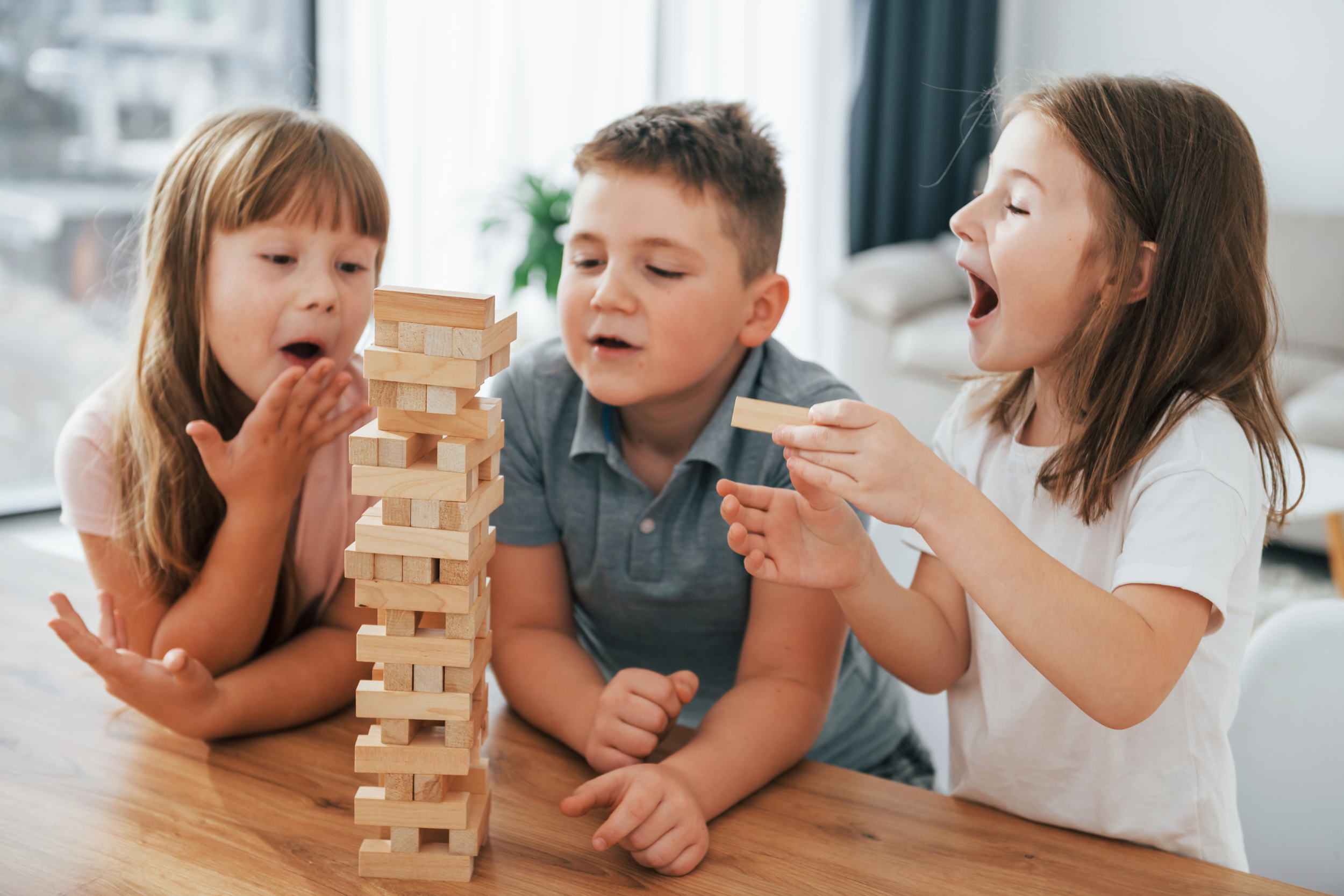 2 focused-jumbling-tower-game-kids-having-fun-domestic-room-daytime-together.jpg